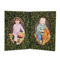 Book with two oval pictures of children on rocking horses on a green leafy background.
