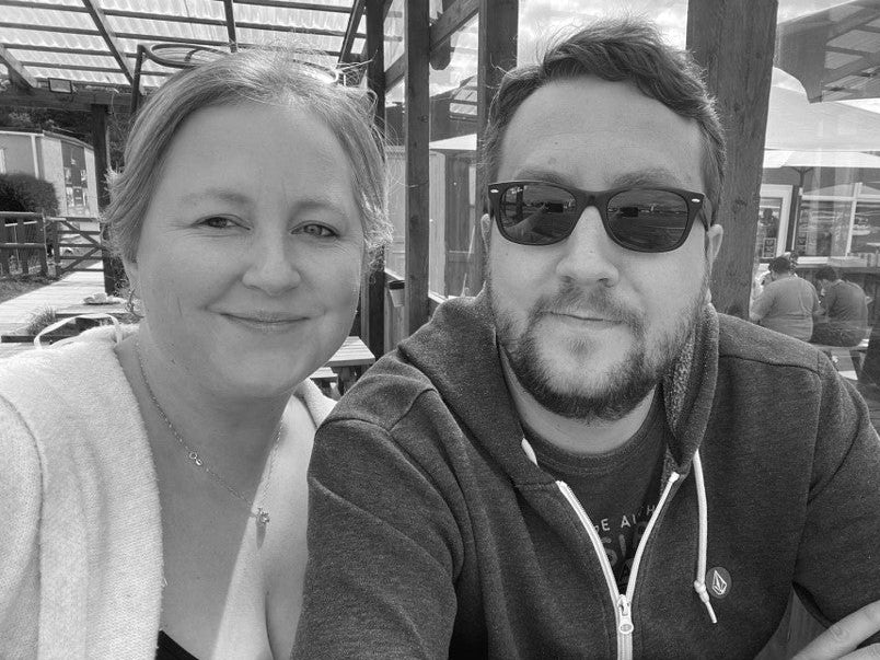 Black and white photo of a man and woman sitting together outdoors.