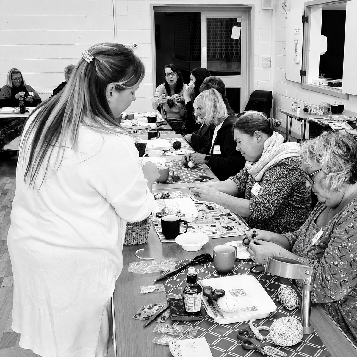 Group of people sitting around a table in a room, engaged in an activity.