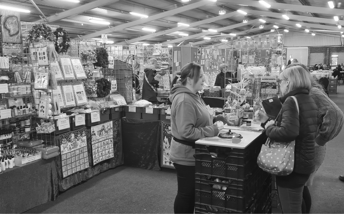 Black and white photo of a store interior with customers and products.