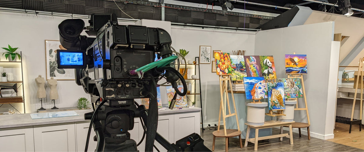 Video camera on a tripod in an art gallery setting with paintings on easels.